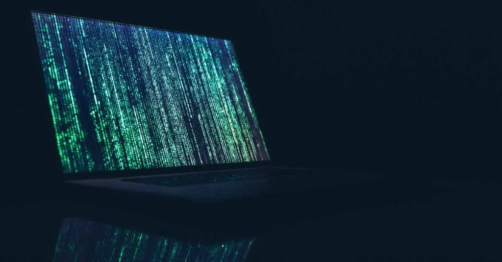 Laptop in dark room with encryption code displayed